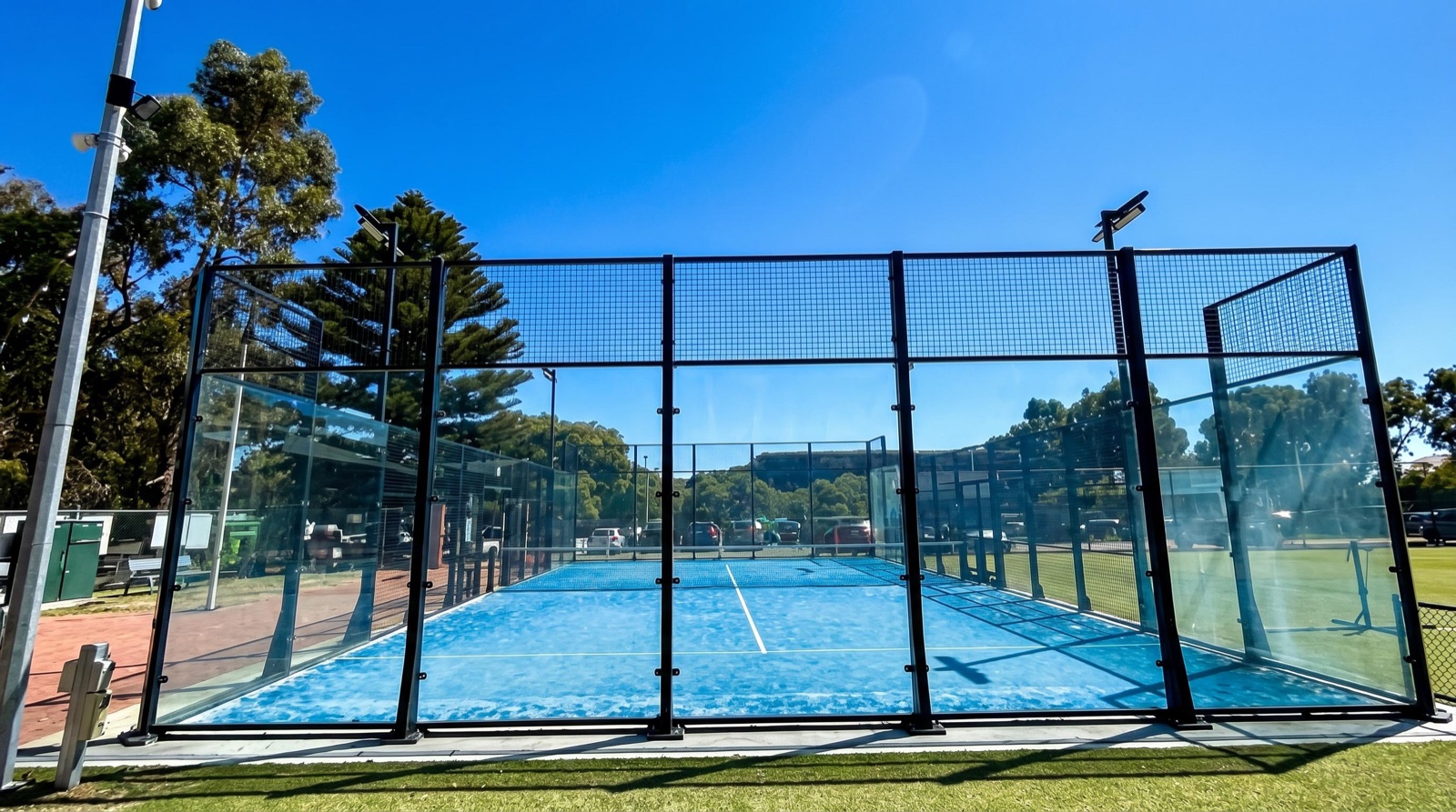 A padel court end structure with a restrained court-side sensing layer